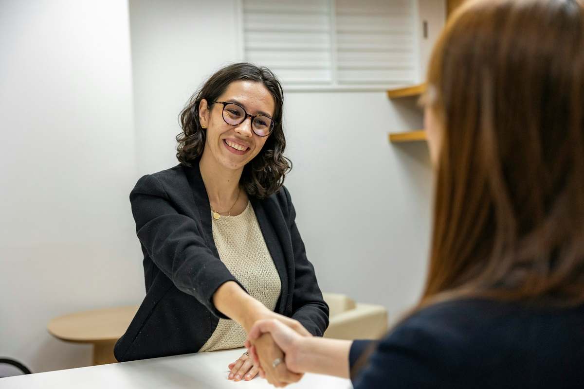 A smiling candidate shaking hands across a desk