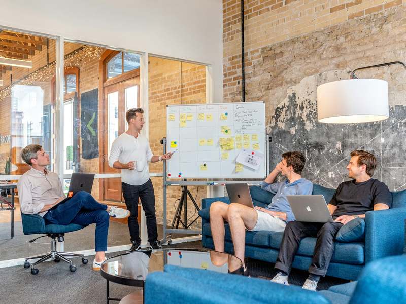 A team on a sofa discussing a whiteboard plan
